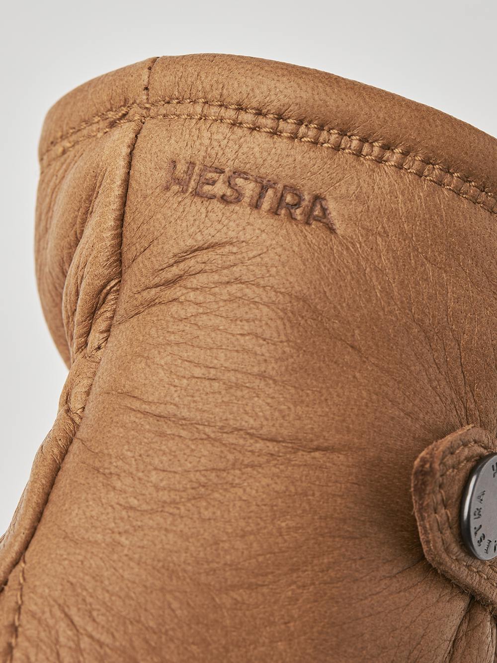 Ljusbrun maskinsydd handske i älgskinn med läderrem och knapp
(2 av 5)