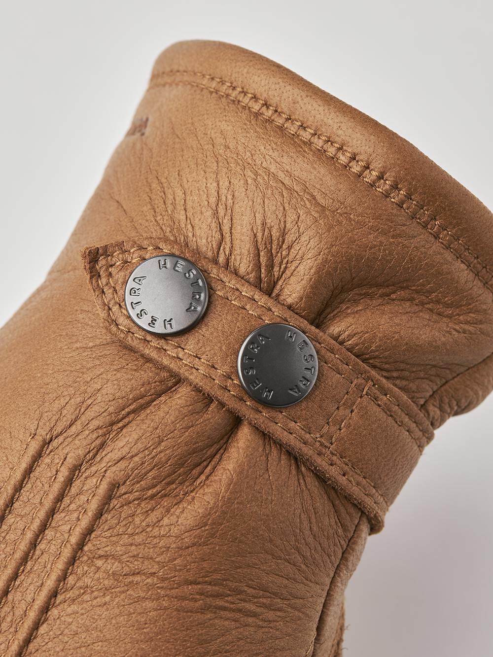 Ljusbrun maskinsydd handske i älgskinn med läderrem och knapp
(3 av 5)