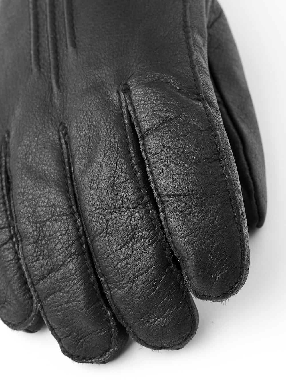 Svart maskinsydd handske i älgskinn med läderrem och knapp
 (2 av 5)