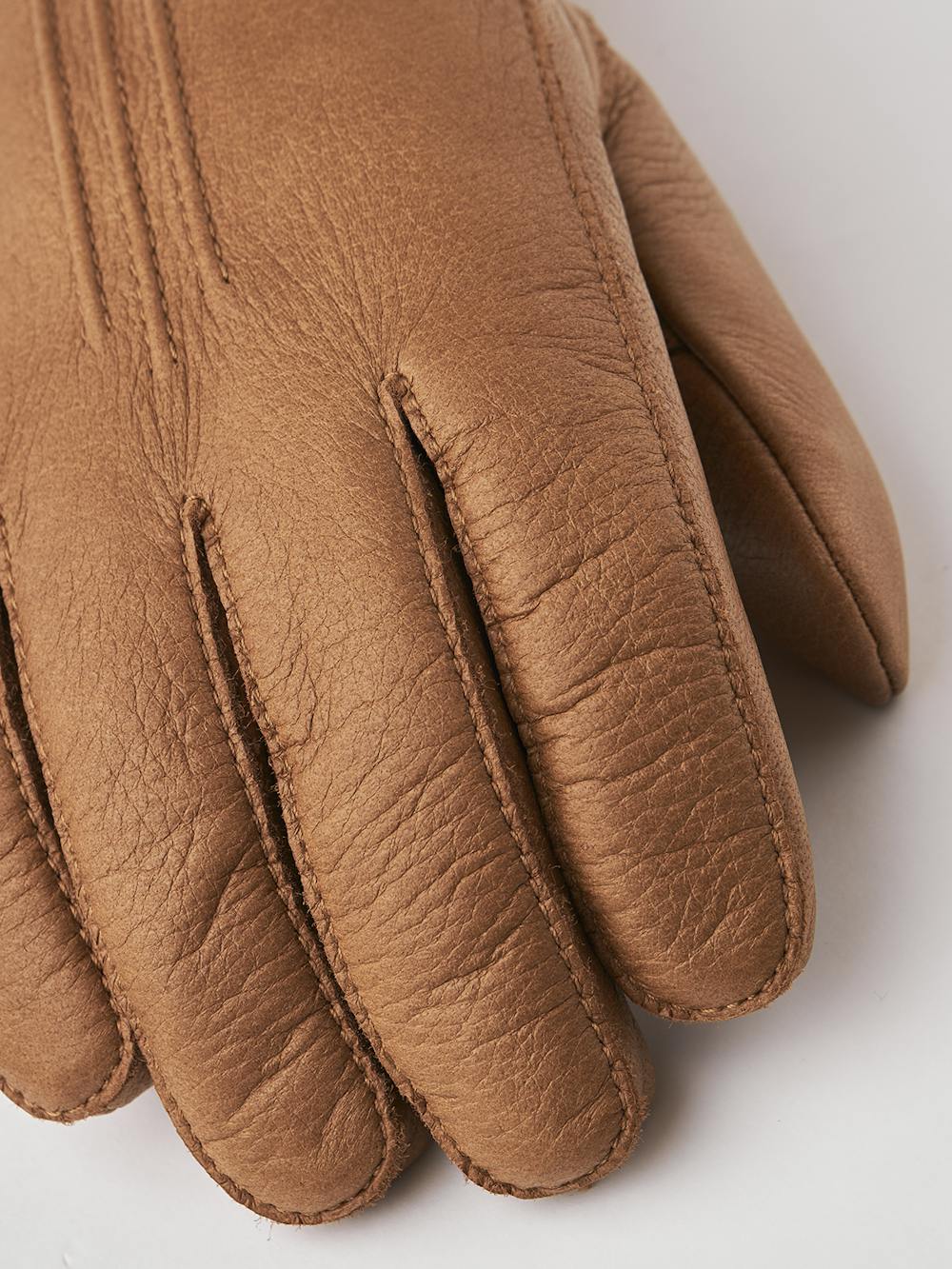 Ljusbrun maskinsydd handske i älgskinn med läderrem och knapp
(4 av 5)