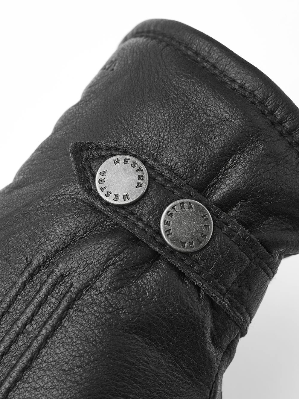 Svart maskinsydd handske i älgskinn med läderrem och knapp
 (4 av 5)