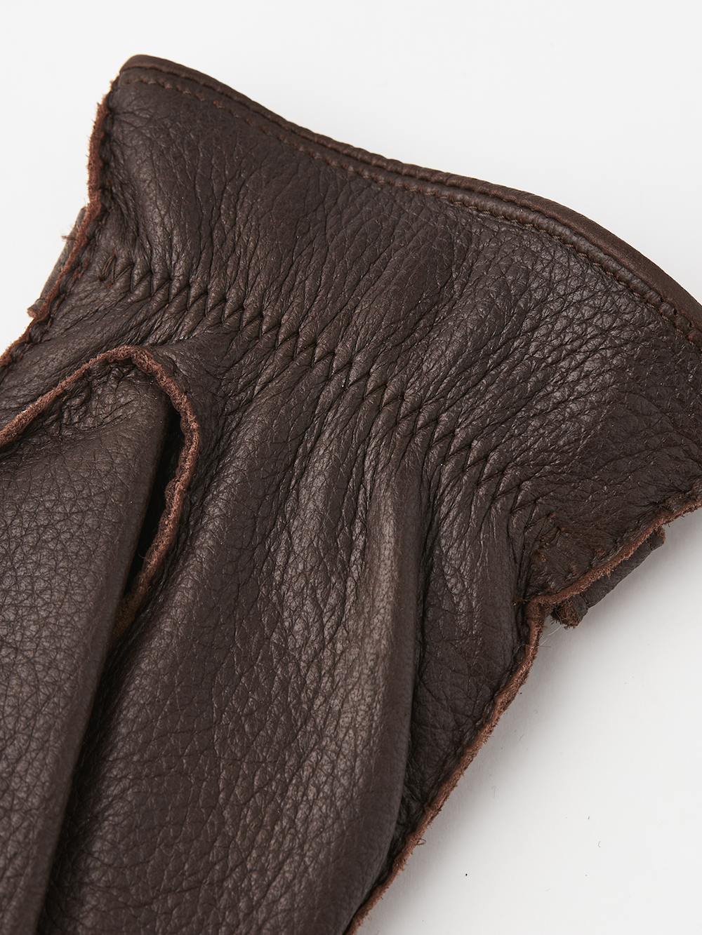 Mörkbrun handsydd handske i älgskinn med läderrem och knapp
(2 av 5)