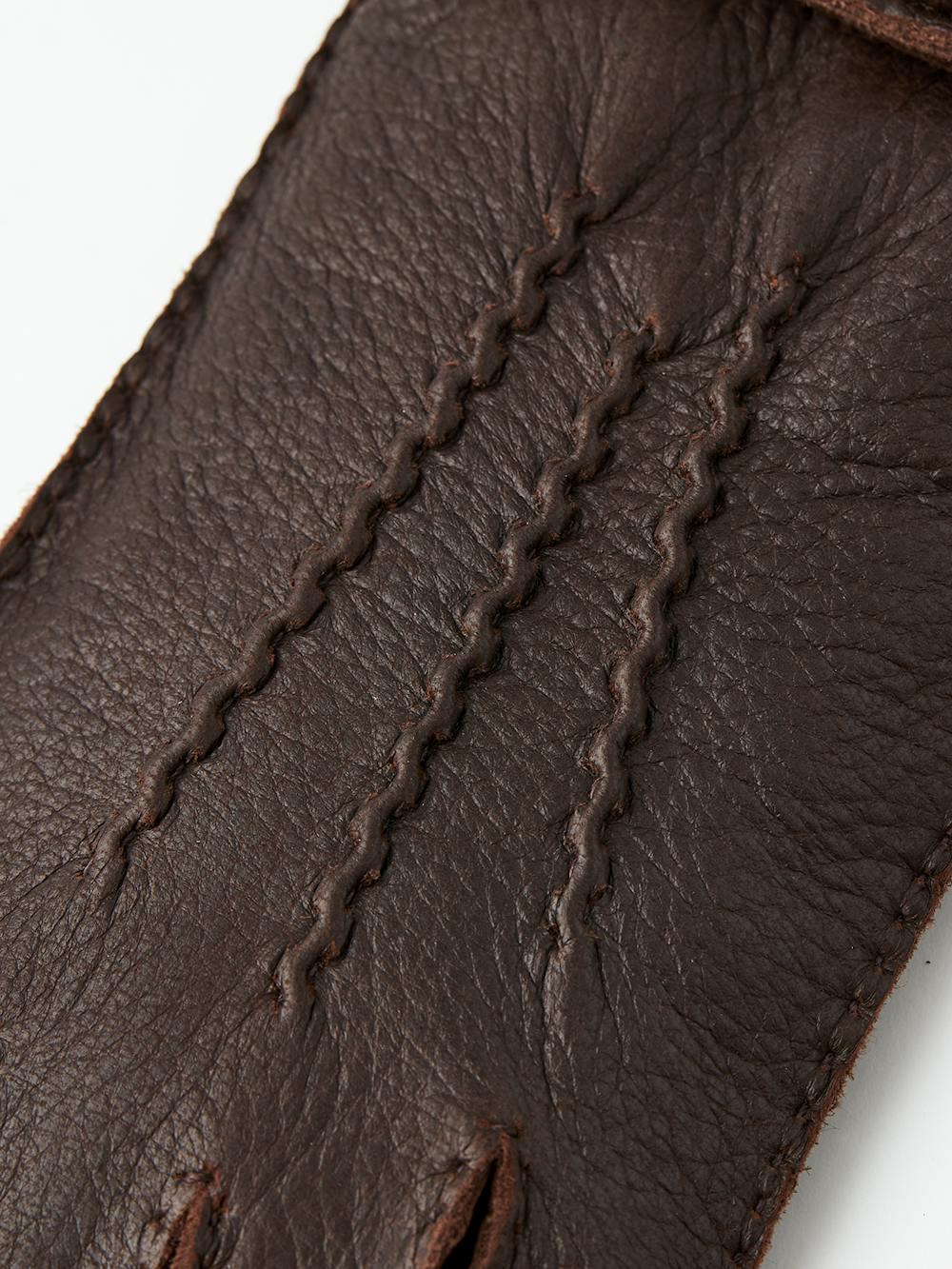 Mörkbrun handsydd handske i älgskinn med läderrem och knapp
(4 av 5)