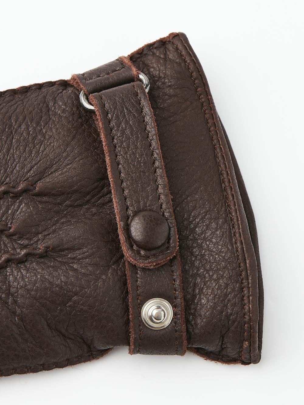 Mörkbrun handsydd handske i älgskinn med läderrem och knapp
 (5 av 5)