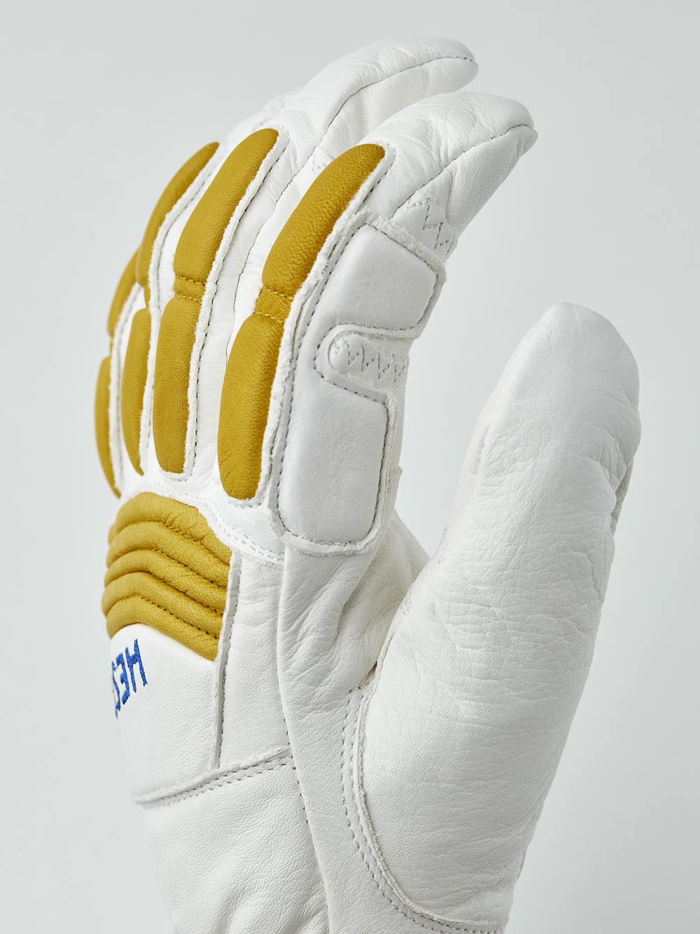 Vit skidhandske i getskinn med gula skydd på ovanhanden och justerbar öppning
 (2 av 5)