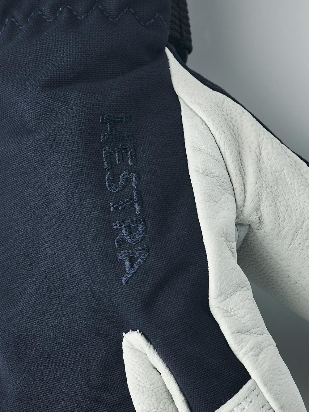 Mörkblå trefingershandske med vitt getskinn i innerhanden
 (3 oder 7)