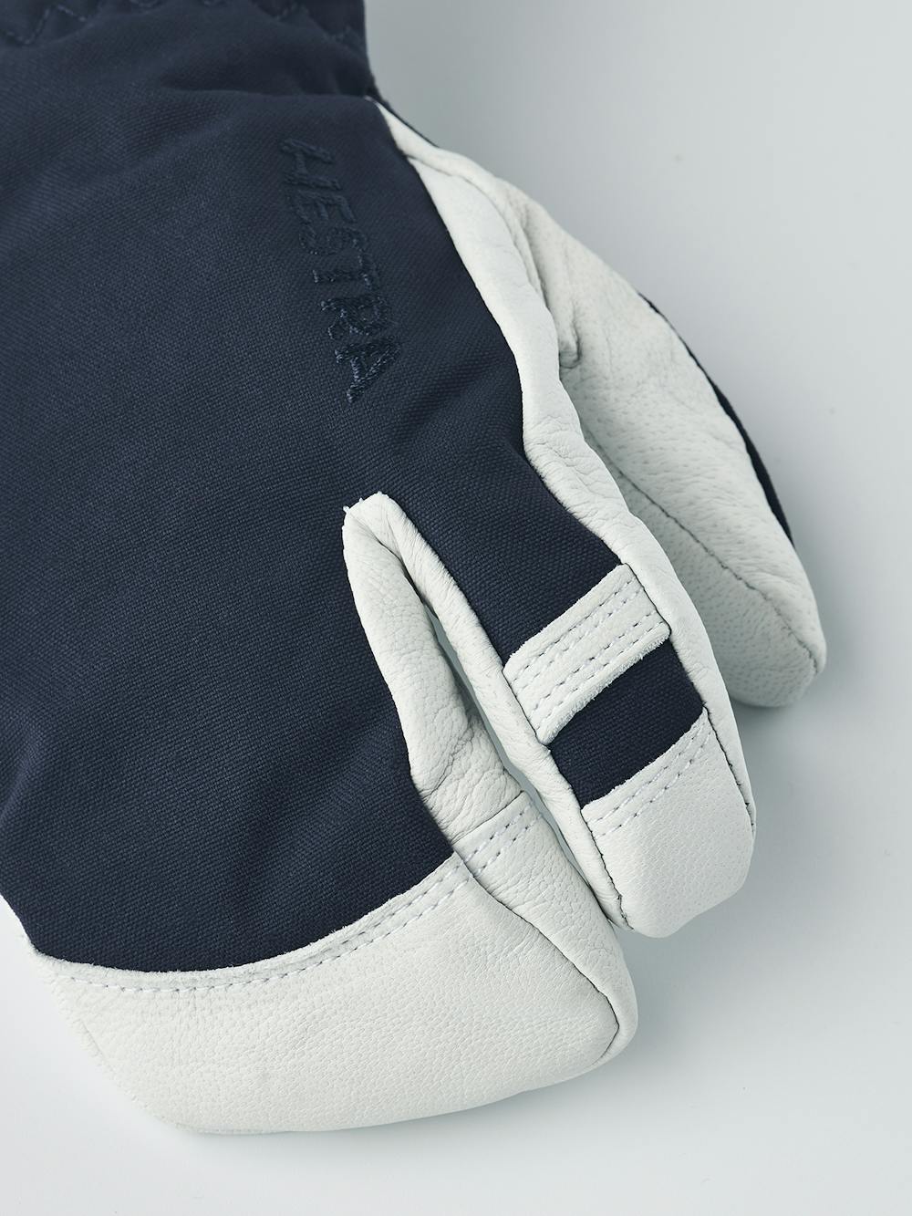 Mörkblå trefingershandske med vitt getskinn i innerhanden
 (2 oder 7)