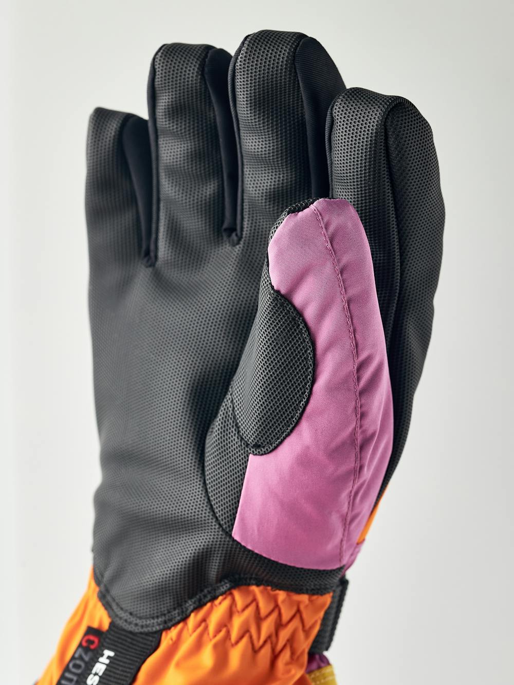 Orange und rosa Kinderhandschuh mit schwarzem Synthetikmaterial an der Innenhand und verstellbarem Handgelenkverschluss (5 oder 6)