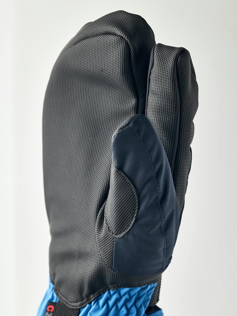 Blå trefingershandske med svart syntetmaterial i innerhanden och handledsjustering
 (3 av 5)