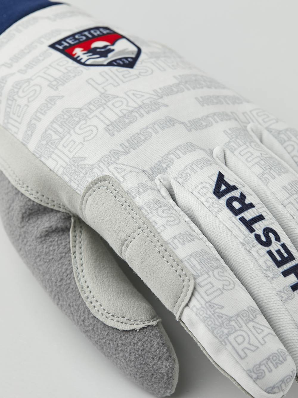 Vit och blå längdskidhandske i tyg med grå innerhand i syntetisk mocka
 (2 av 5)