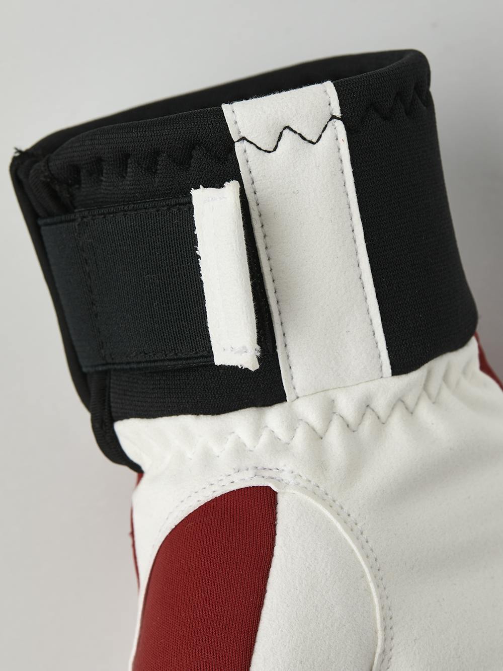 Röd tumhandske i tyg med vit innerhand i syntetisk mocka
 (6 av 6)