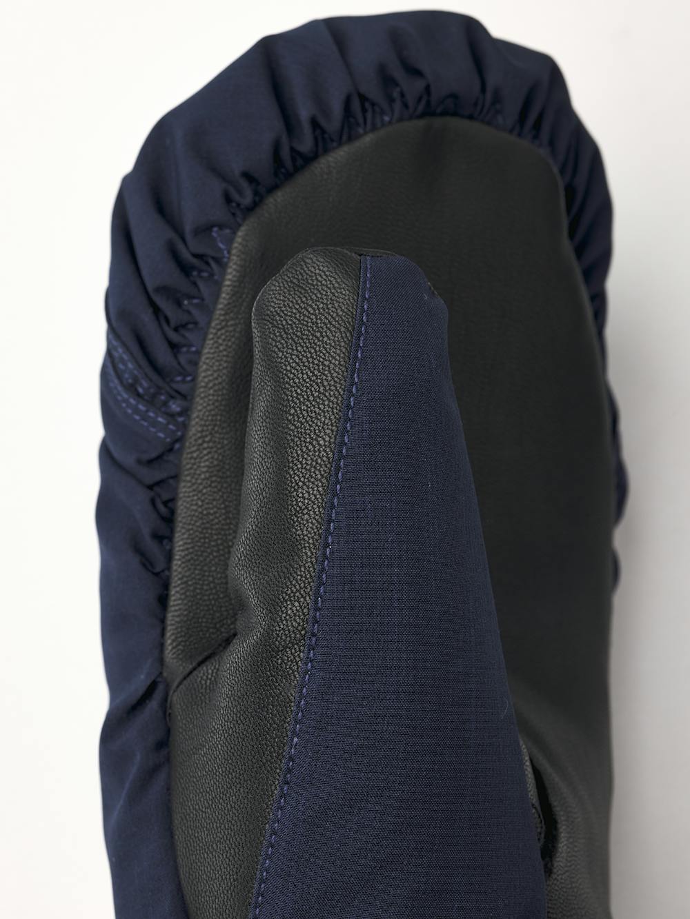 Mörkblå tumhandske i tyg med svart lammnappa i innerhanden och handledsjustering
(2 av 6)