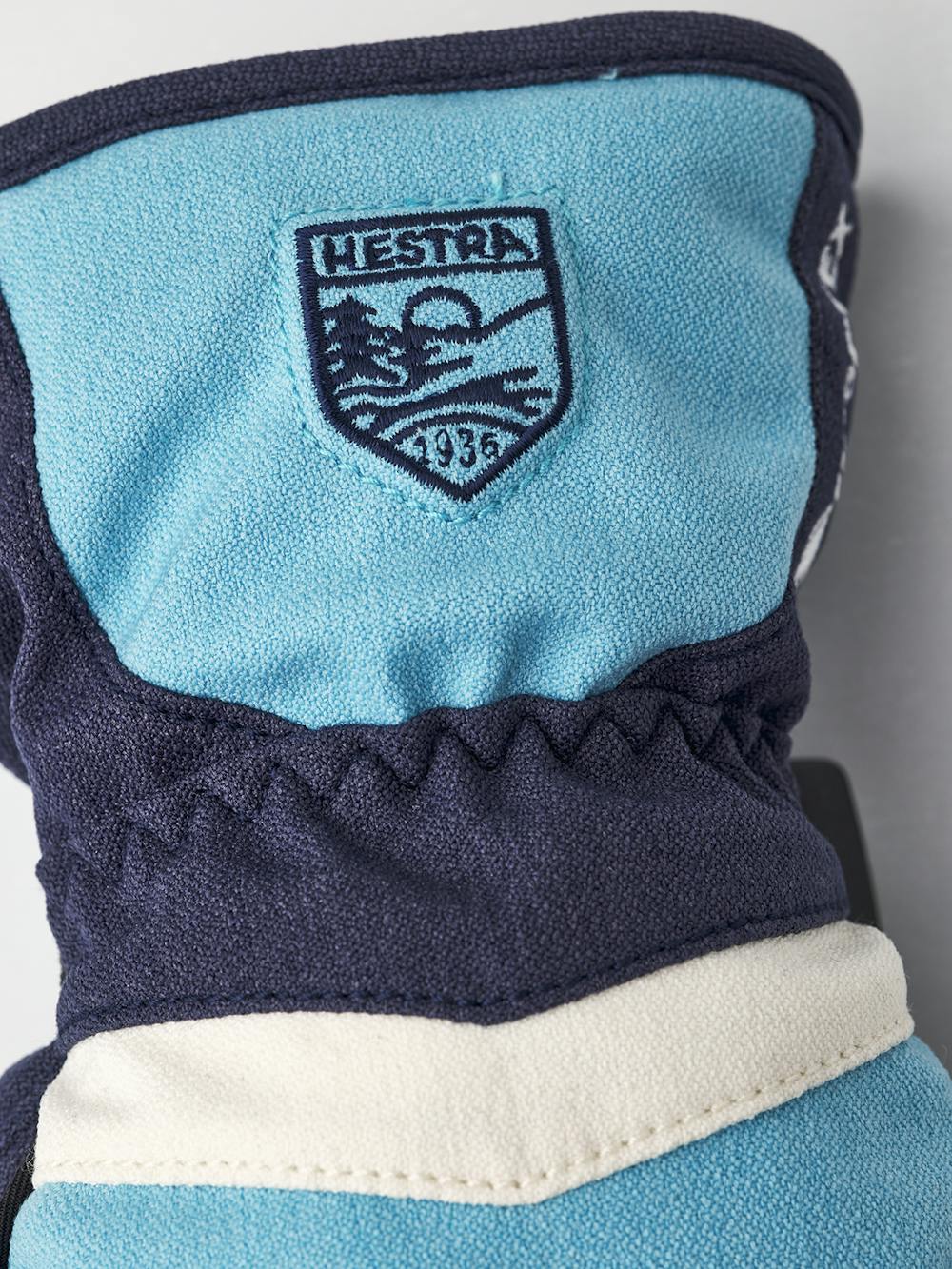 Blå barnhandske i tyg med svart syntetmaterial i innerhanden och handledsjustering 
 (2 av 6)